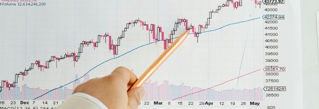 Close-up of a hand pointing at a financial chart on a whiteboard, showing data analysis.